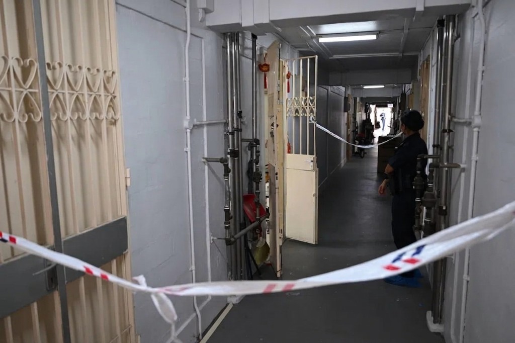 Police cordon tape at a residential block corridor during investigation